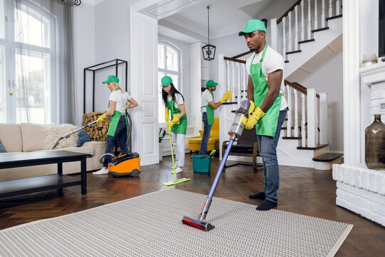 Cleaning team performing House Clean Out Services Kent WA, vacuuming carpet and mopping floors in a bright modern home